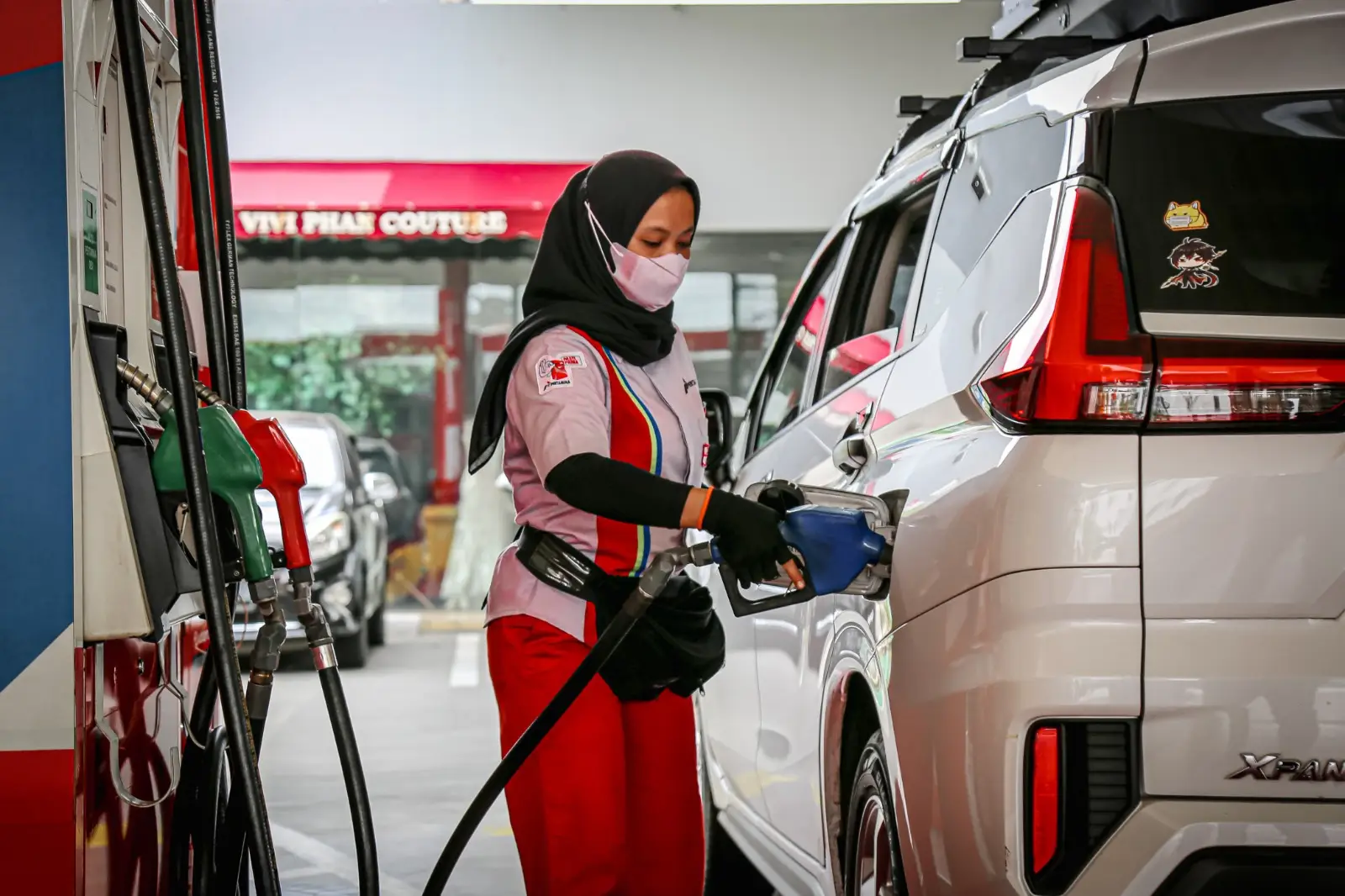 Seorang pekerja di sebuah SPBU tengah melayani pembeli