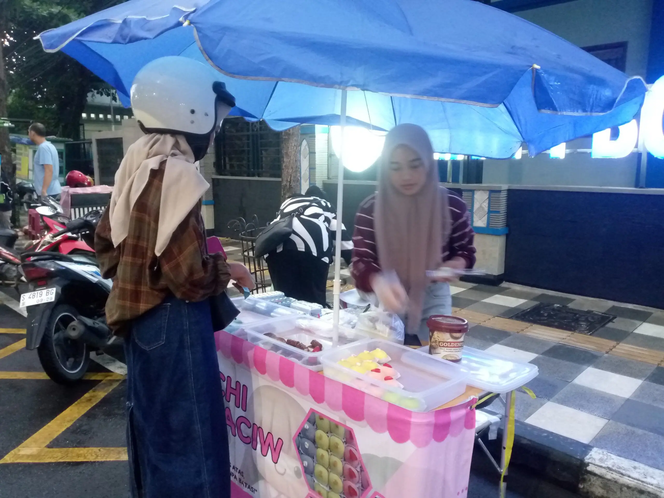 seorang pembeli, membeli mochi dari stand mochi di pinggir jalan