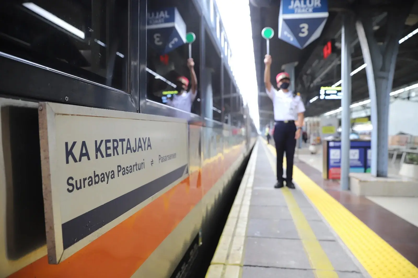 Petugas kereta api memberi tanda keberangkatan di samping KA Kertajaya Surabaya Pasar Turi